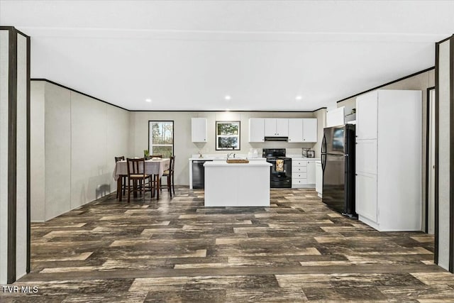 kitchen featuring dark hardwood / wood-style flooring, sink, black appliances, white cabinets, and a center island