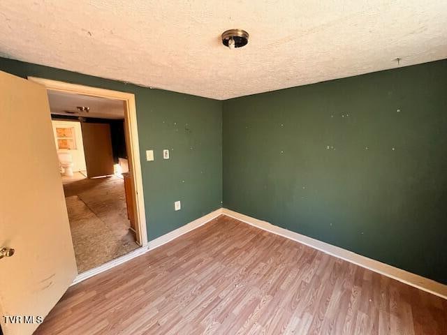 spare room featuring a textured ceiling and hardwood / wood-style flooring