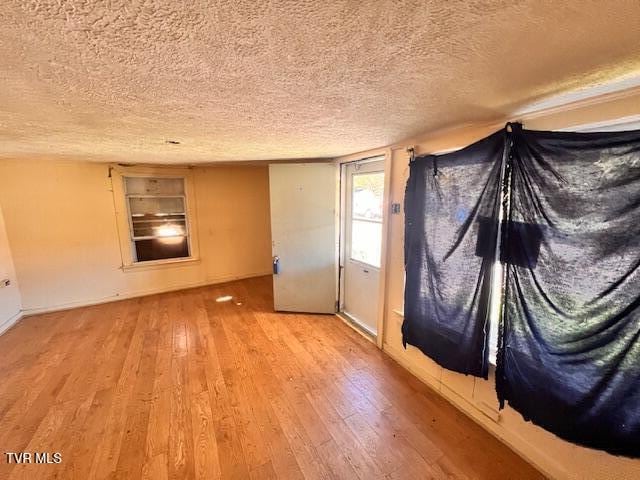 spare room with a textured ceiling and light wood-type flooring