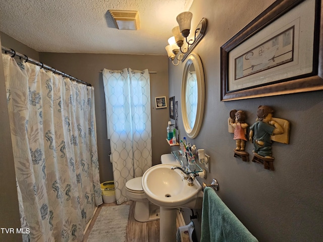 bathroom with toilet, a shower with curtain, wood-type flooring, sink, and a textured ceiling