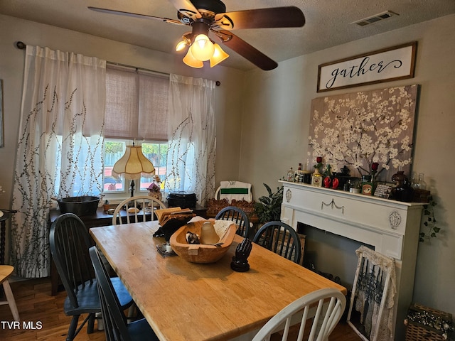 dining room with hardwood / wood-style floors, a textured ceiling, and ceiling fan