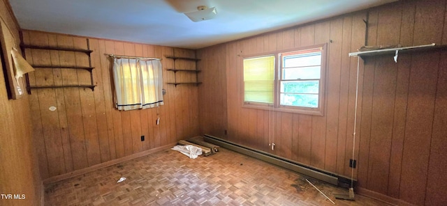 spare room with parquet flooring, wooden walls, and a baseboard radiator