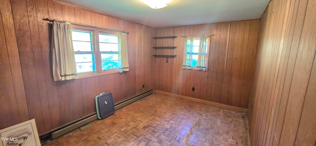 unfurnished room featuring baseboard heating, wooden walls, and parquet floors