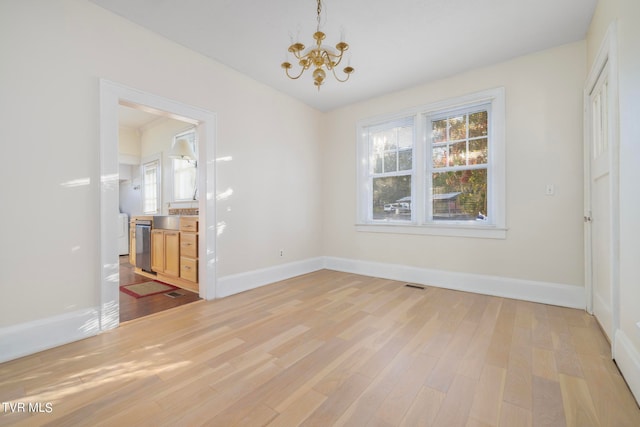 unfurnished dining area with light hardwood / wood-style floors and an inviting chandelier