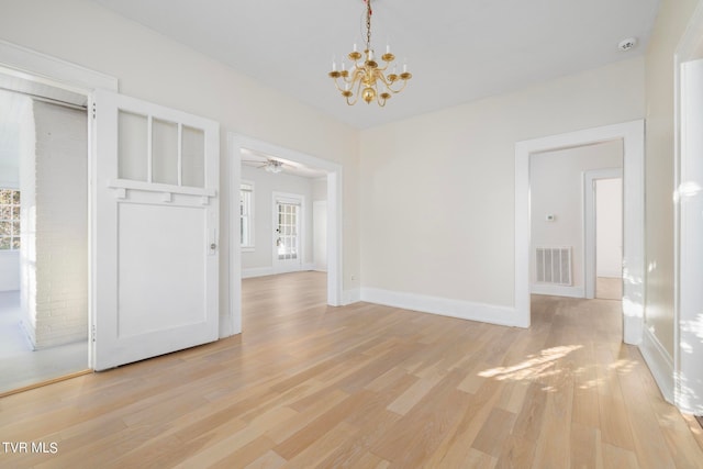 unfurnished dining area featuring a healthy amount of sunlight, light hardwood / wood-style flooring, and ceiling fan with notable chandelier