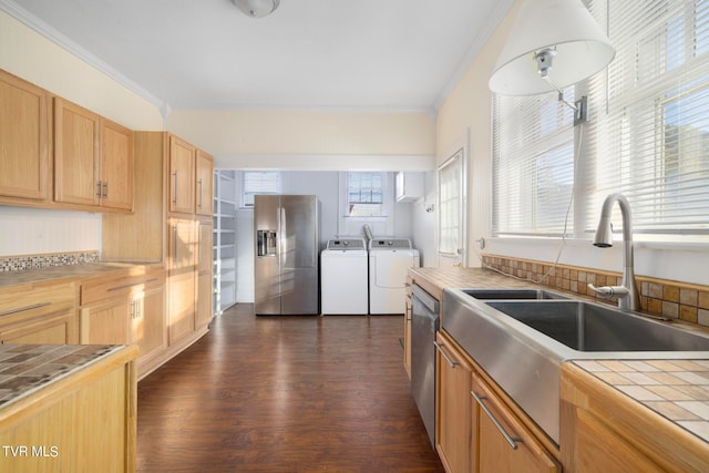 kitchen with dark hardwood / wood-style floors, tile countertops, stainless steel appliances, ornamental molding, and washing machine and clothes dryer