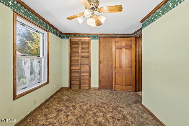 unfurnished bedroom featuring crown molding, a closet, carpet flooring, and ceiling fan