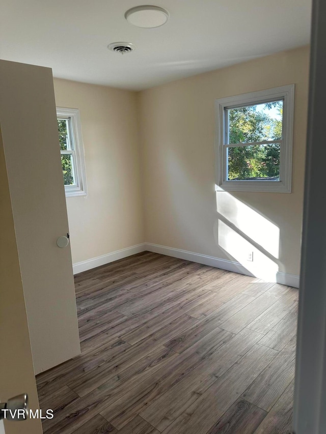 spare room featuring dark wood-type flooring and plenty of natural light