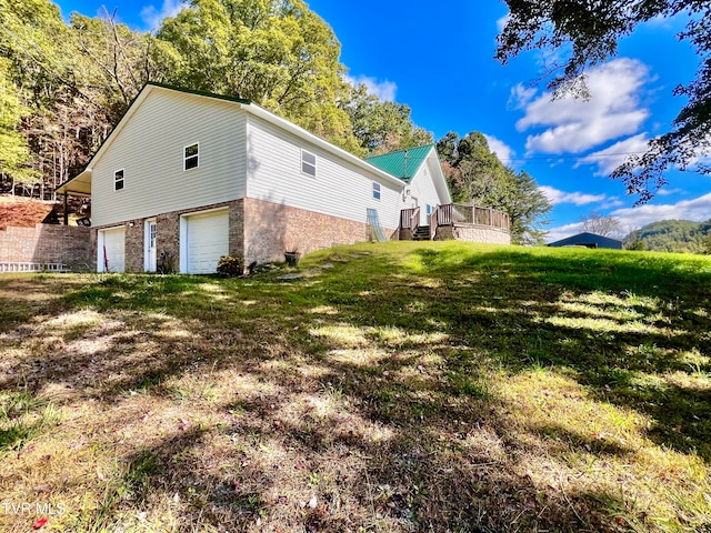 view of side of property with a yard, a garage, and a deck