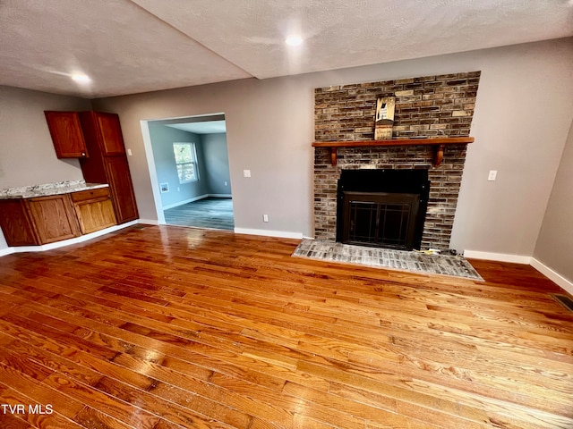 unfurnished living room featuring a fireplace, a textured ceiling, and hardwood / wood-style flooring