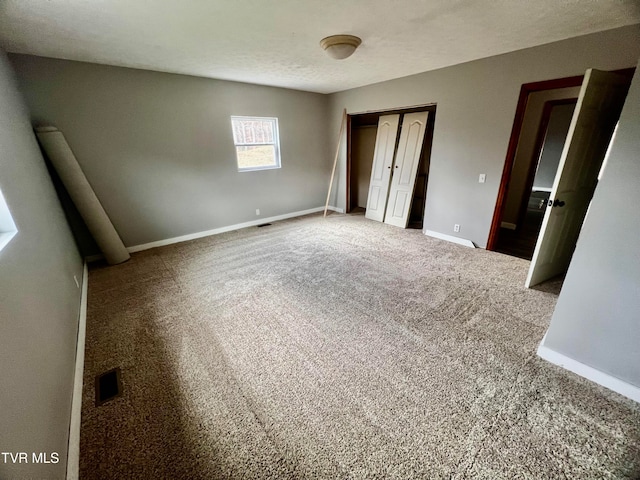 unfurnished bedroom featuring carpet flooring, a textured ceiling, and a closet