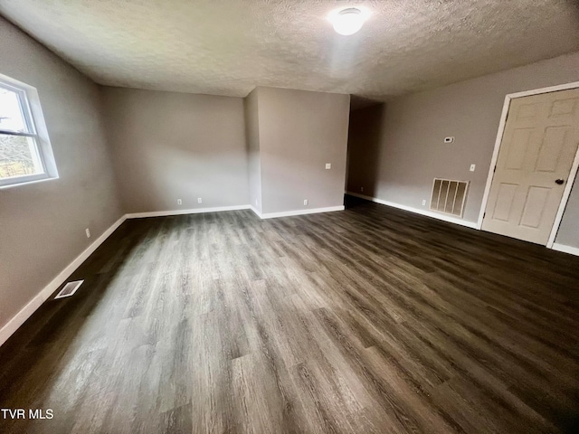 spare room with a textured ceiling and dark wood-type flooring