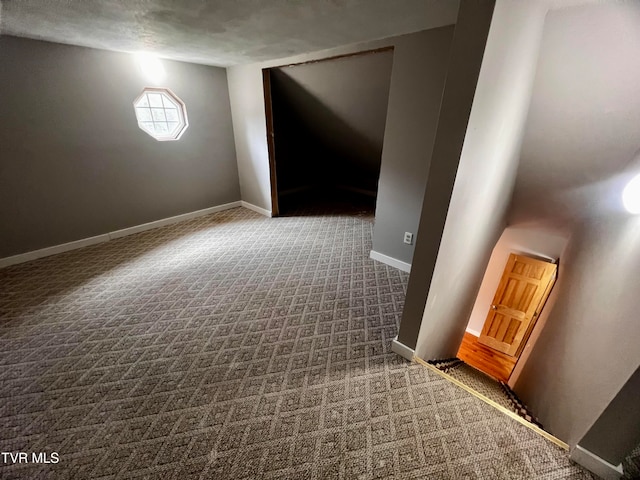 spare room featuring carpet floors, a textured ceiling, and vaulted ceiling