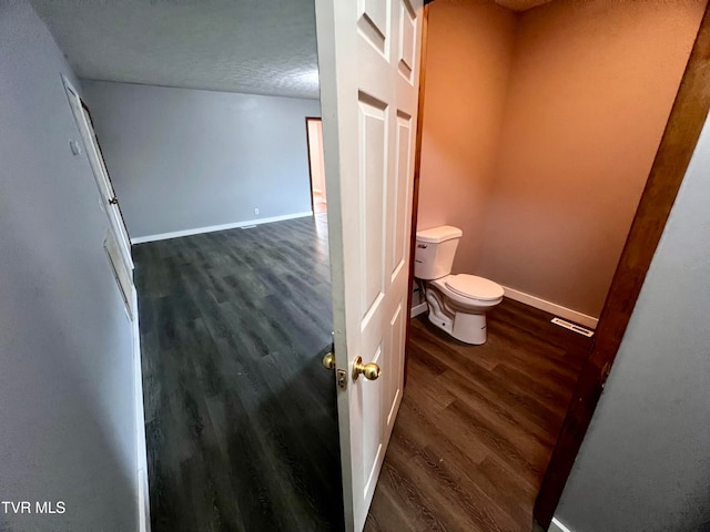 bathroom with wood-type flooring, a textured ceiling, and toilet