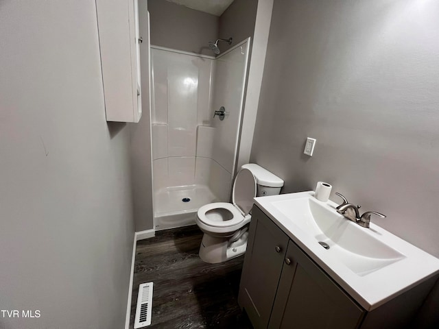 bathroom with a shower, toilet, vanity, and hardwood / wood-style flooring