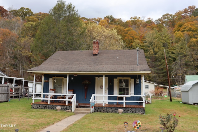 view of front of house with a porch, a front yard, and a shed