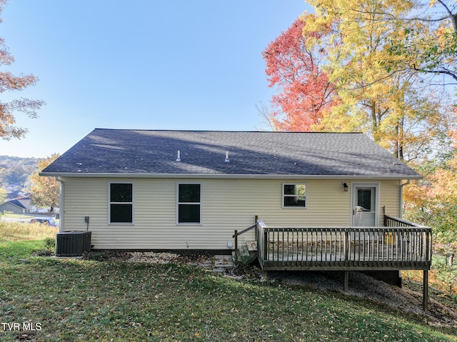 back of property featuring central air condition unit, a deck, and a lawn