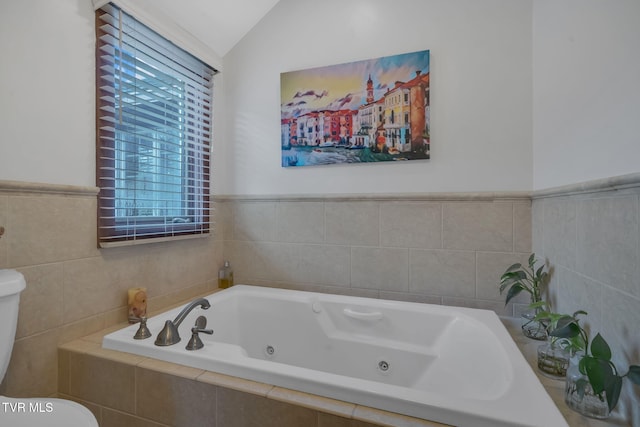 bathroom featuring toilet, a relaxing tiled tub, vaulted ceiling, and tile walls