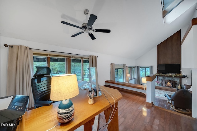 office space with wood-type flooring, a large fireplace, ceiling fan, and a healthy amount of sunlight