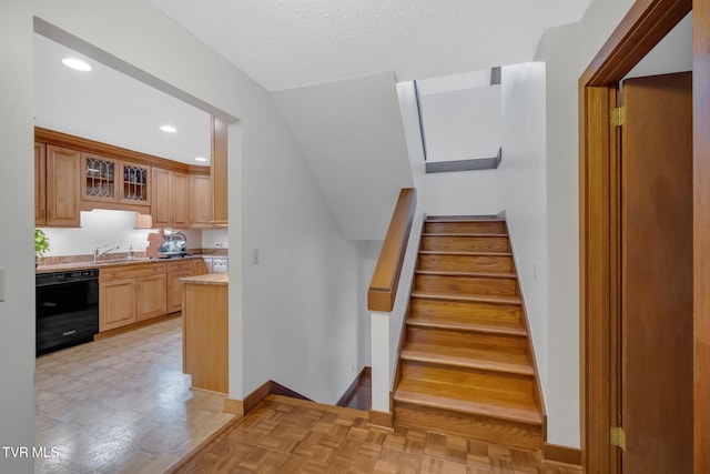 staircase with a textured ceiling and sink