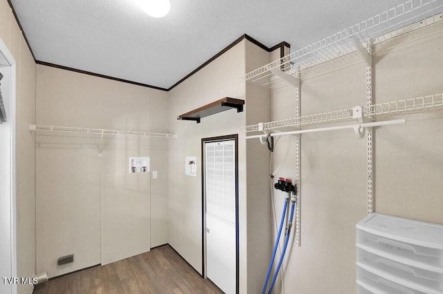 laundry room featuring hookup for a washing machine, hardwood / wood-style floors, a textured ceiling, and crown molding