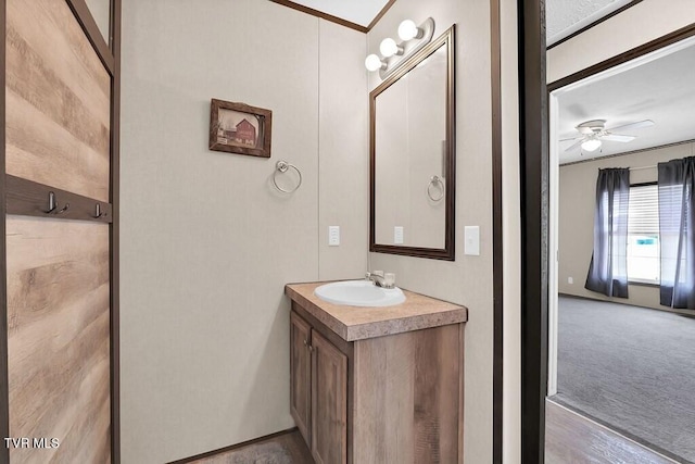 bathroom featuring ceiling fan, ornamental molding, and vanity