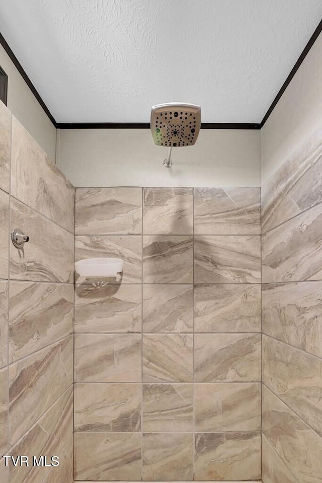 bathroom featuring tiled shower, ornamental molding, and a textured ceiling