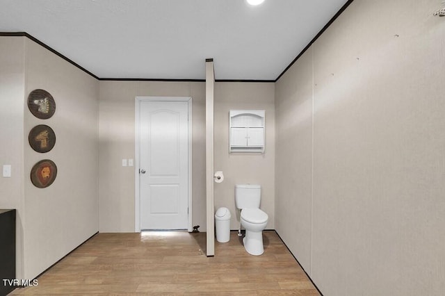 bathroom with ornamental molding, toilet, and wood finished floors