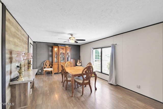 dining space featuring a ceiling fan, a textured ceiling, and wood finished floors