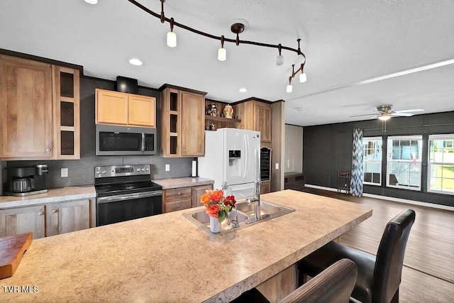 kitchen with ceiling fan, appliances with stainless steel finishes, open shelves, a sink, and light countertops