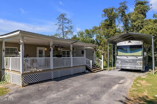 manufactured / mobile home featuring a porch, driveway, and a carport