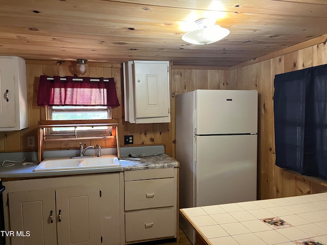 kitchen with wooden walls, wooden ceiling, sink, and white refrigerator