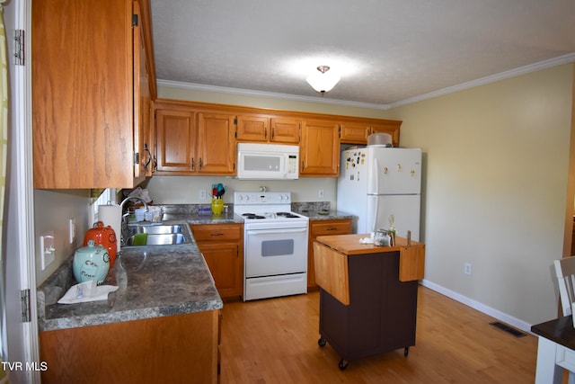 kitchen featuring white appliances, sink, a center island, light hardwood / wood-style floors, and crown molding