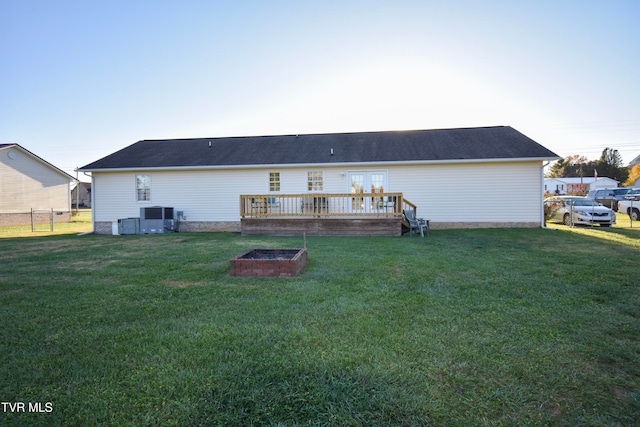 back of property featuring a yard, a wooden deck, and an outdoor fire pit