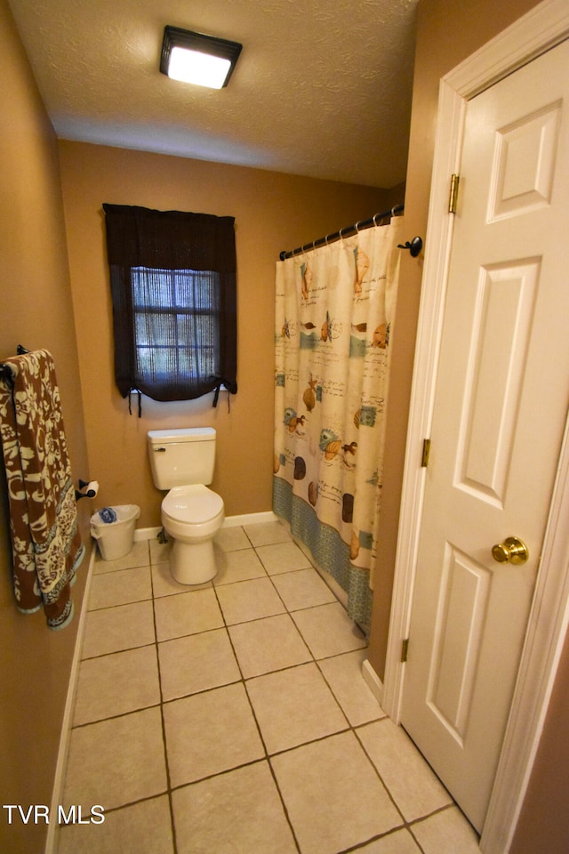 bathroom featuring toilet, a textured ceiling, and tile patterned flooring