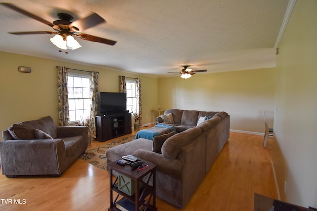 living room featuring crown molding, a textured ceiling, light wood-type flooring, and ceiling fan