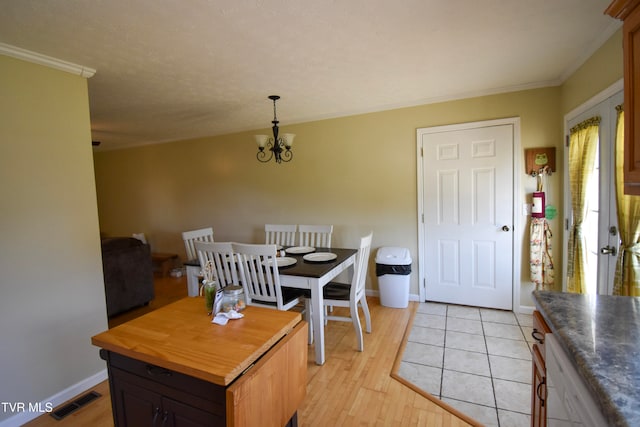 dining area with light hardwood / wood-style flooring, ornamental molding, and a notable chandelier