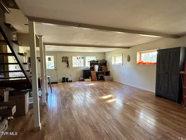 unfurnished living room with a wealth of natural light, beamed ceiling, and wood-type flooring