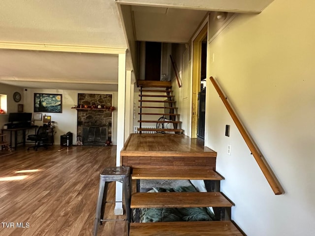 stairway with a stone fireplace and hardwood / wood-style flooring