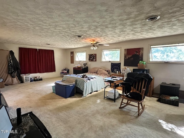 carpeted living room with ceiling fan, a healthy amount of sunlight, and a textured ceiling