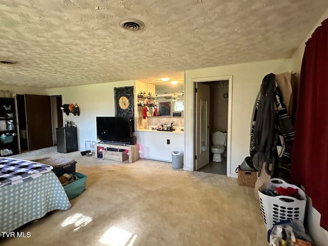 carpeted bedroom with connected bathroom and a textured ceiling