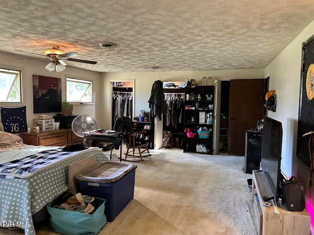 carpeted bedroom featuring multiple windows, a textured ceiling, a closet, and ceiling fan