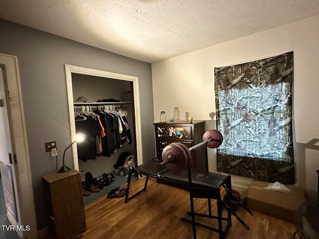 exercise area featuring a textured ceiling and wood-type flooring