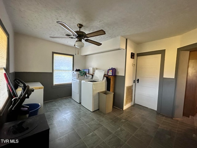 clothes washing area with a textured ceiling, separate washer and dryer, and ceiling fan