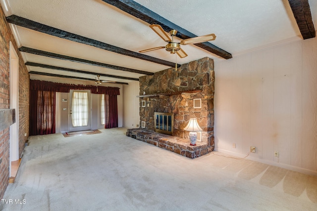 unfurnished living room featuring ceiling fan, beam ceiling, carpet, a fireplace, and a textured ceiling