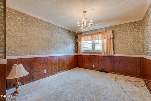 spare room featuring an inviting chandelier, crown molding, light carpet, and a textured ceiling