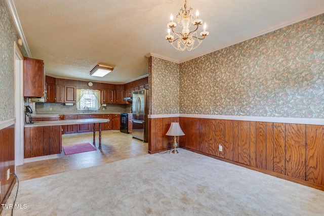 kitchen featuring sink, pendant lighting, crown molding, stainless steel fridge, and electric stove