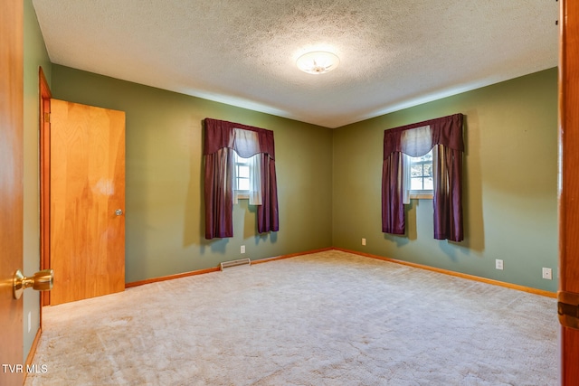 unfurnished room with light colored carpet and a textured ceiling