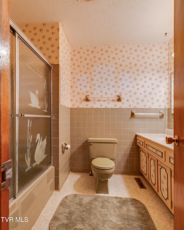 full bathroom featuring enclosed tub / shower combo, tile walls, tile patterned flooring, vanity, and toilet