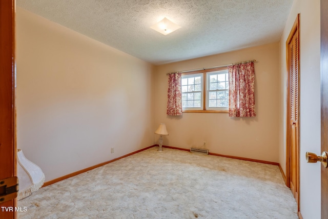 empty room featuring a textured ceiling and carpet flooring